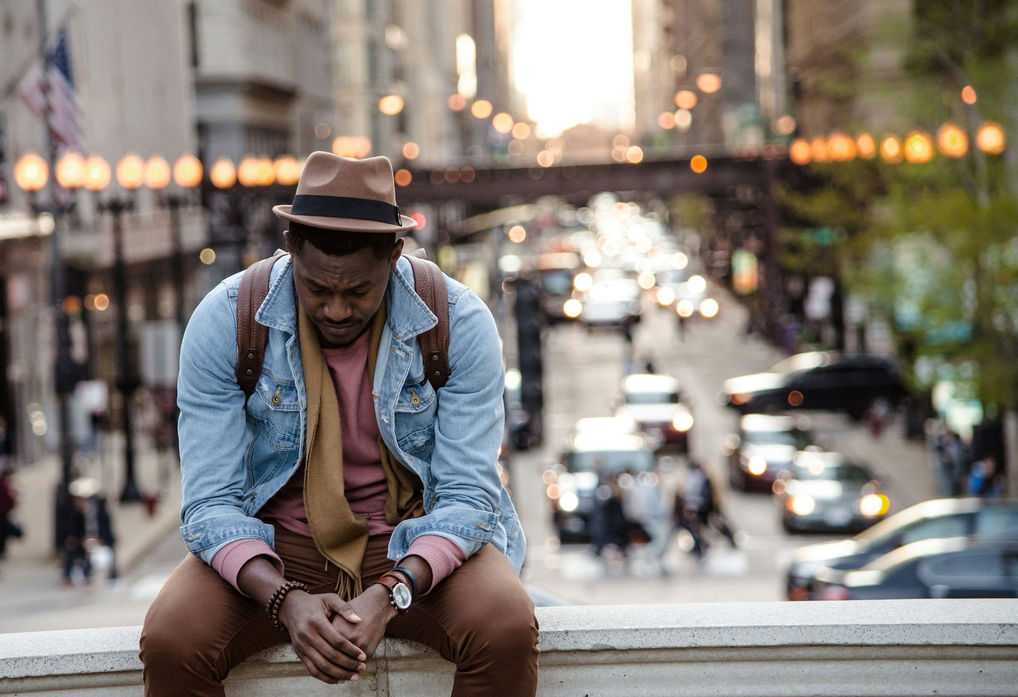 a-man-in-a-leather-jacket-looking-down-while-sitting-on-a-ledge-in-a-city.jpg A man in a leather jacket looking down while sitting on a ledge in a city